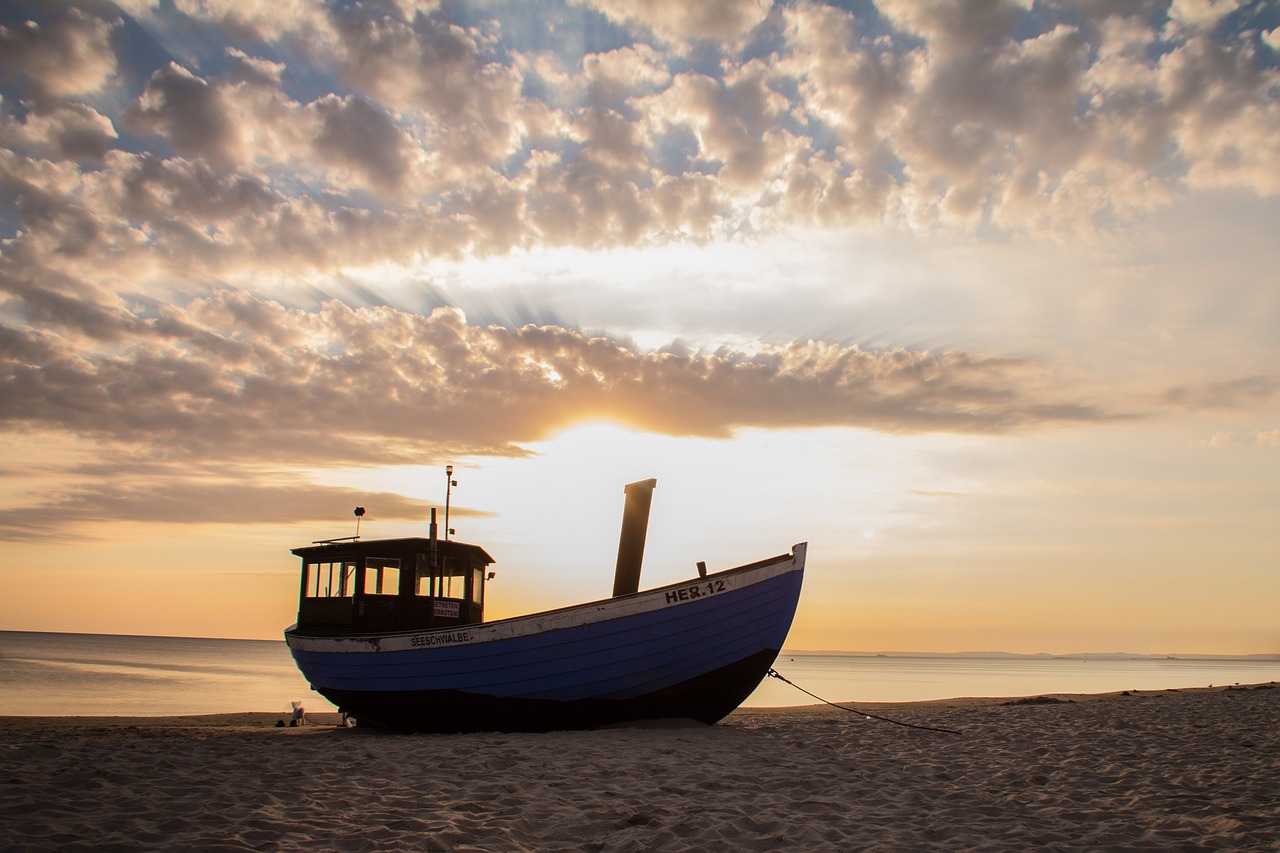 Łódka na plaży na tle mora i zachodzącego słońca